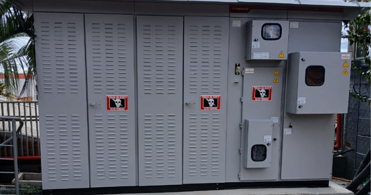 Cubículo de média tensão instalado em ambiente industrial, com painel elétrico metálico branco e conexões elétricas visíveis